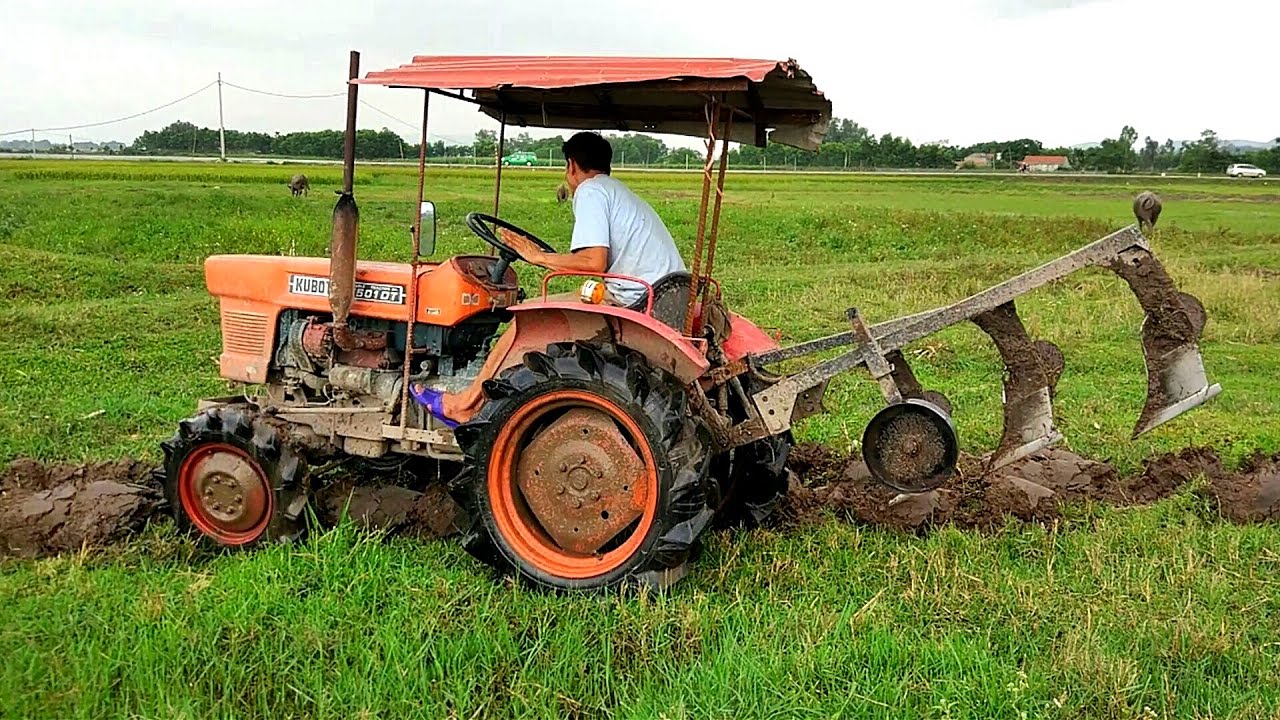 Máy cày đang hoạt động trên ruộng, bánh xe lăn trên đất ẩm